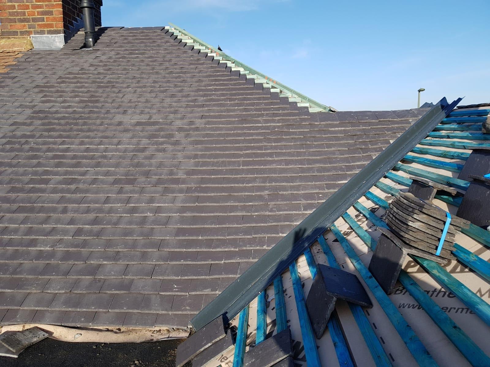 Newly completed slate roof under a clear blue sky