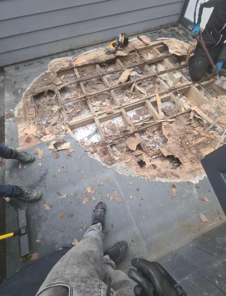Flat roof opened up to reveal a rotten timber deck before repair