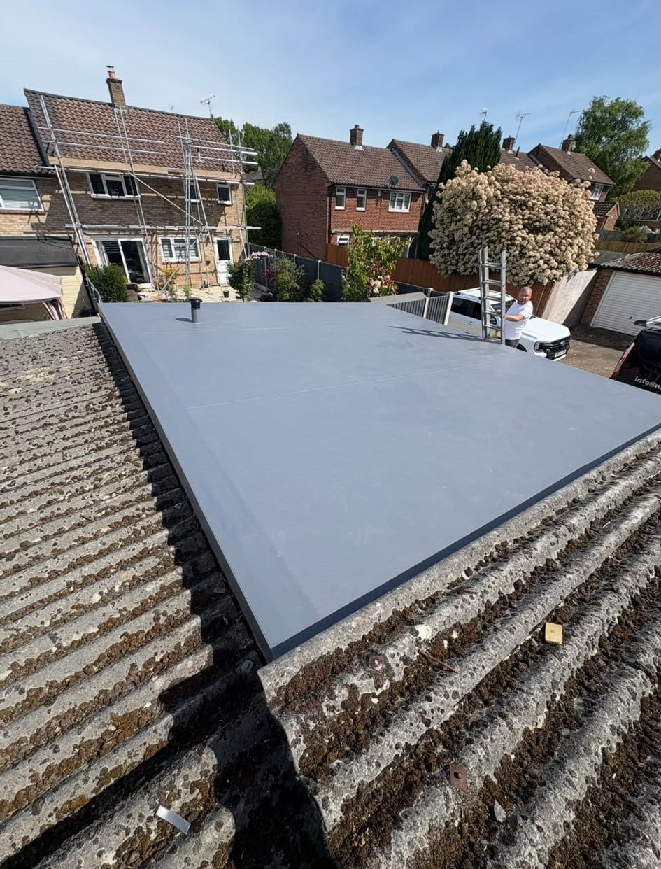 New grey GRP fibreglass flat roof on an outbuilding with 1930s houses behind