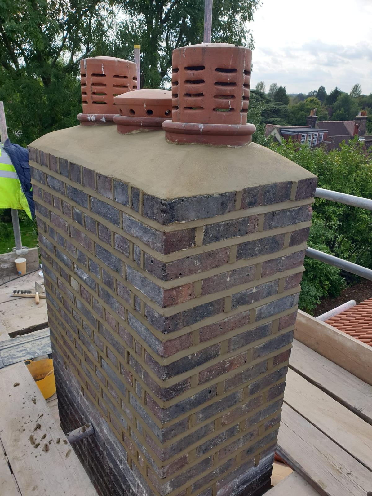 Rebuilt brick chimney stack with two new pots, seen from the scaffold